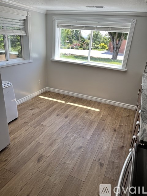 A kitchen with a white dishwasher and wooden flooring.