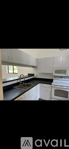 A kitchen with white cabinets and black countertops.