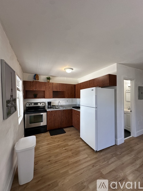 A kitchen with a white fridge and wooden floors.