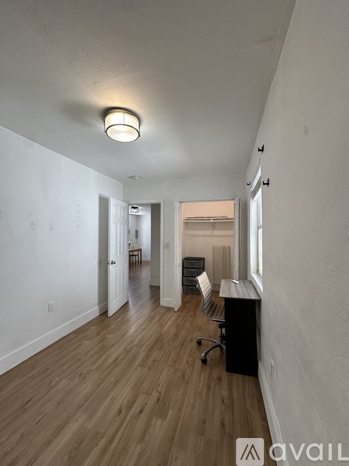 A long hallway with a light on the ceiling and a desk with a chair in the middle.