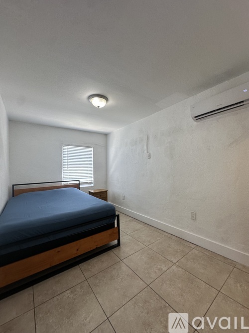 A bedroom with a bed, tiled floor, and a window with blinds.