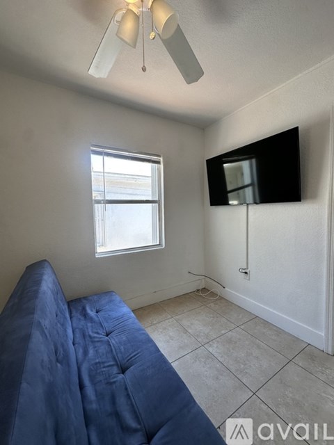A living room with a blue couch and a flat screen TV mounted on the wall.