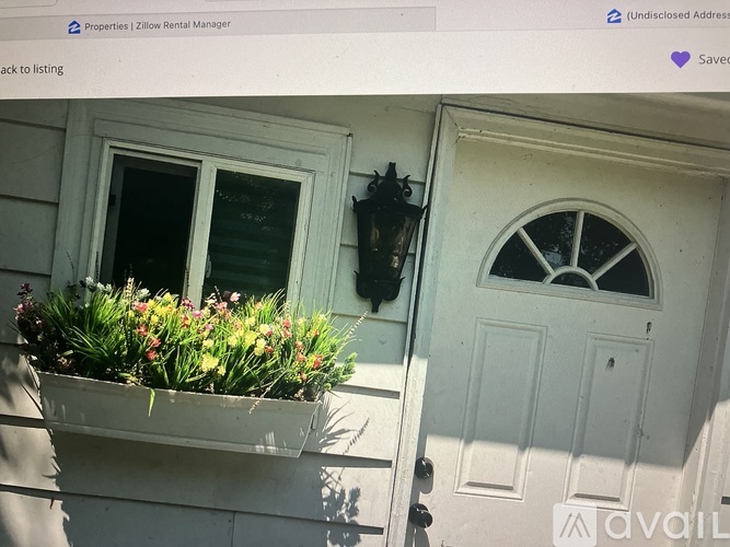A white door with a window above it and a planter box with flowers in front of it.