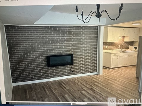 A modern kitchen with a brick wall and a television.