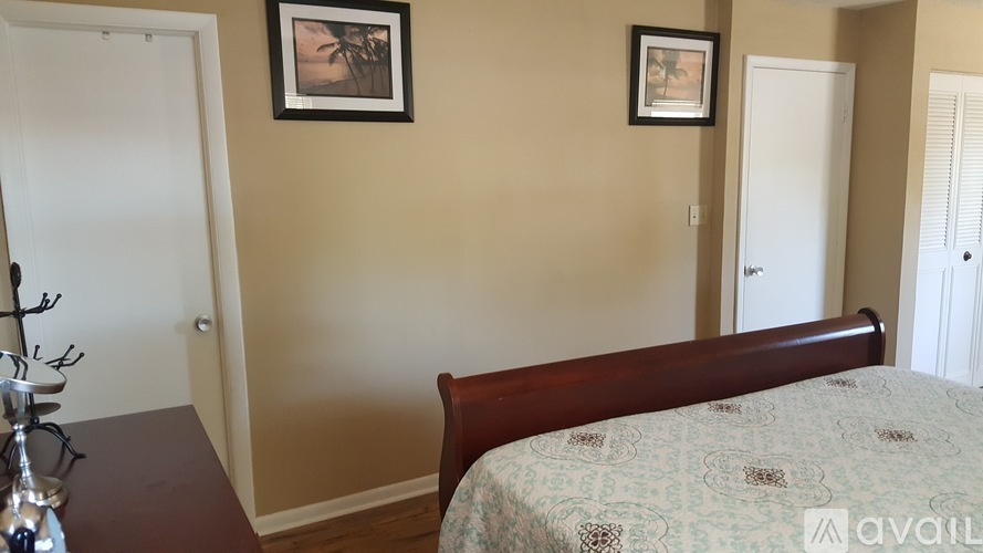 A bedroom with a bed, a table, and two pictures on the wall.