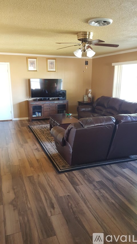 A living room with a brown leather couch and a wooden floor.