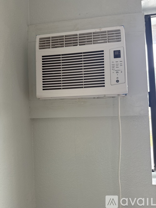 A white air conditioner is mounted on a white wall.