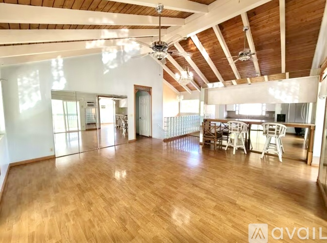 A spacious room with wooden floors and a high ceiling with exposed beams.