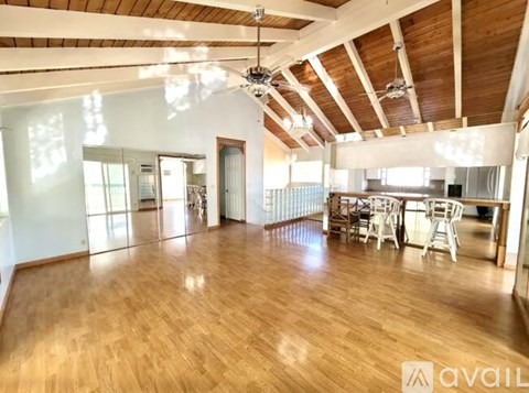A spacious room with wooden floors and a high ceiling with exposed beams.