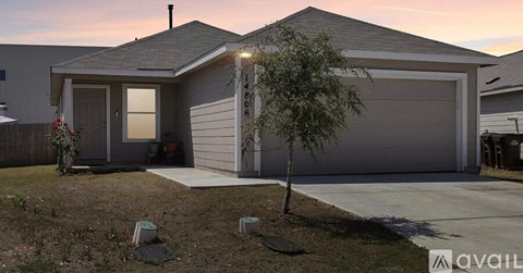 A house with a garage and a tree in front of it.