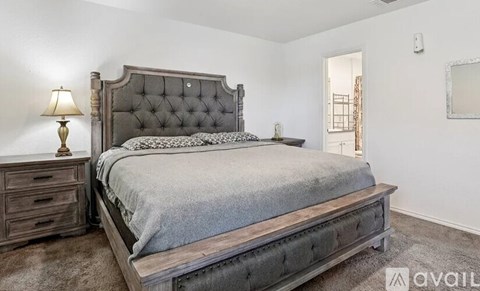 A bedroom with a large bed, wooden headboard, and a lamp on the nightstand.