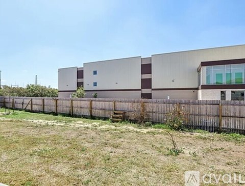 A large industrial building with a fence in front of it.
