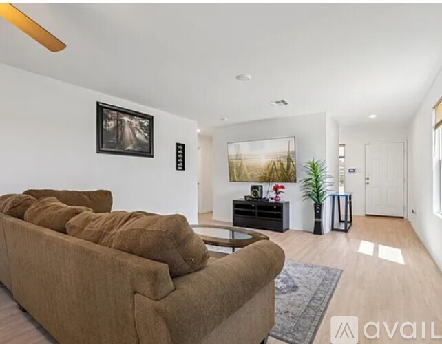 A living room with a brown couch and a painting on the wall.