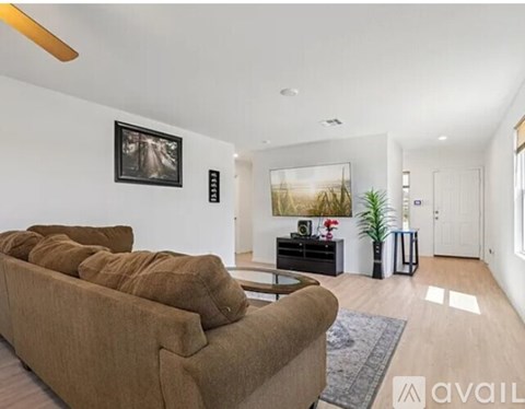 A living room with a brown couch and a painting on the wall.