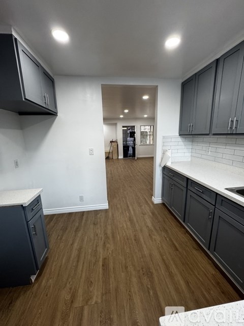 A kitchen with dark wood floors and white walls.