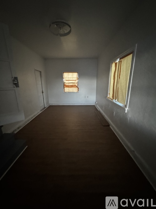 A room with wooden floors and a window with curtains.