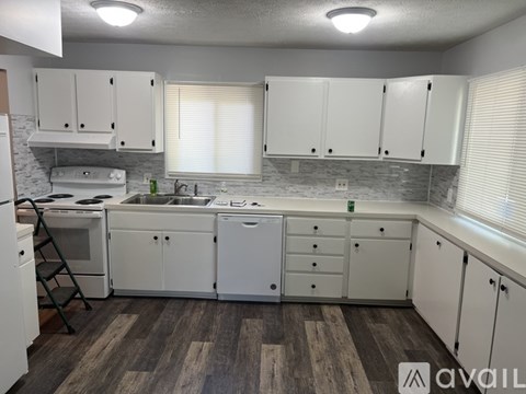 A kitchen with white cabinets and a wooden floor.