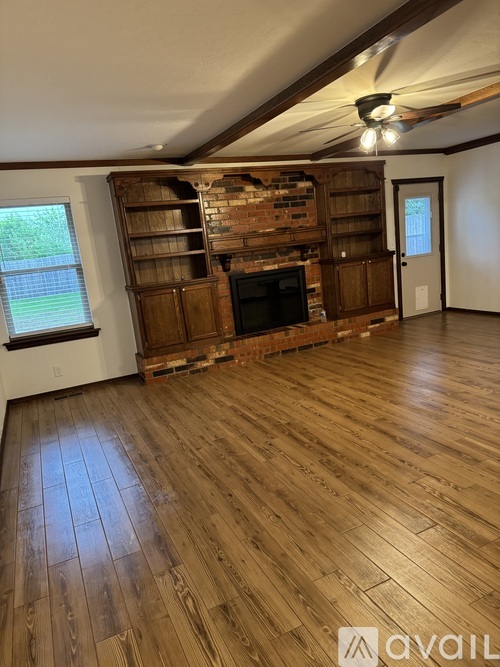 A room with wooden floors and a brick fireplace.