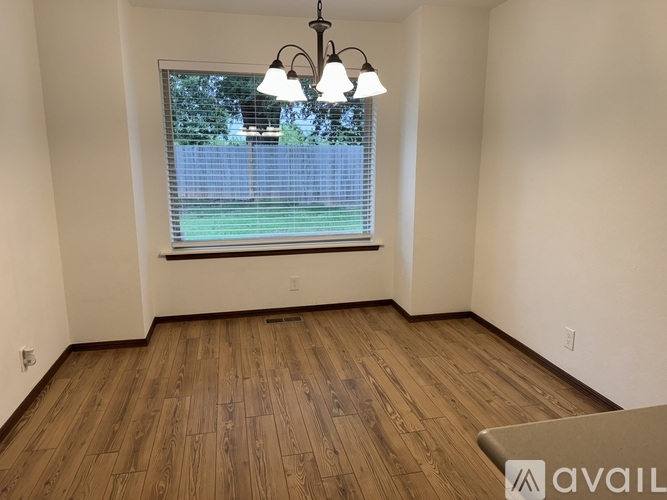 A room with wooden flooring and a window with blinds.