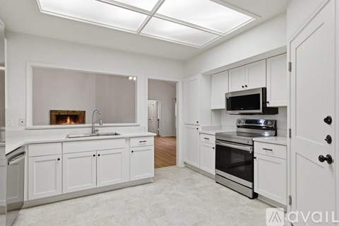 A modern kitchen with white cabinets and stainless steel appliances.