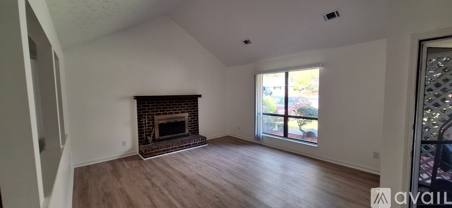 A large empty room with a fireplace and wooden floors.