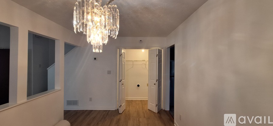 A room with a chandelier and a white wall.