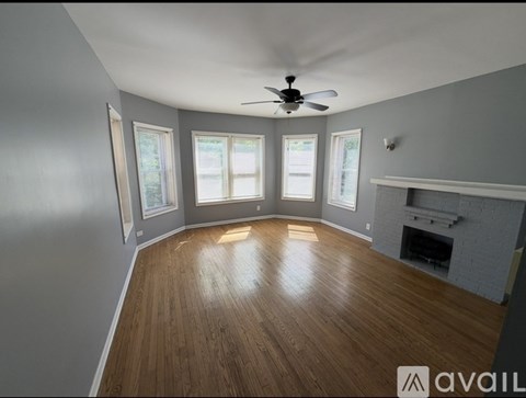 A spacious room with wooden flooring and a fireplace.