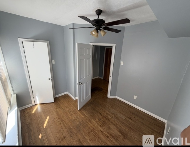 A room with a ceiling fan and wooden flooring.