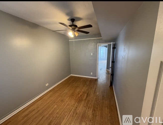A room with a ceiling fan and wooden flooring.