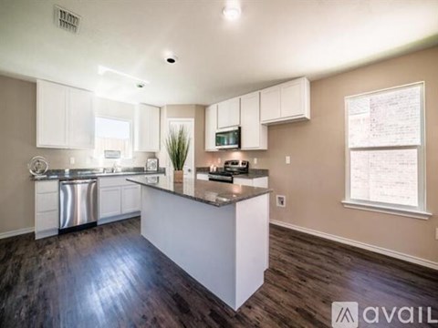 A kitchen with white cabinets and a wooden floor.