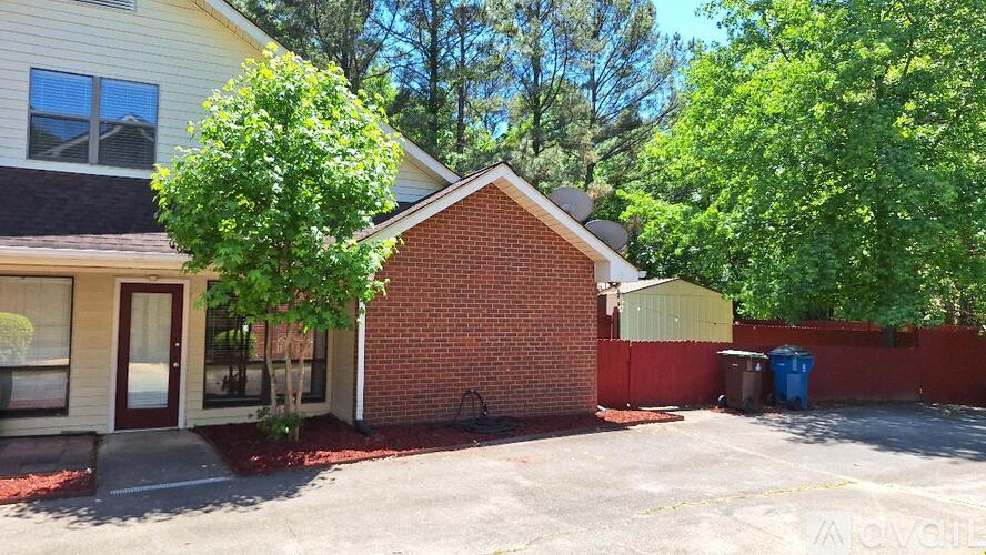 A house with a red brick wall and a tree in front.