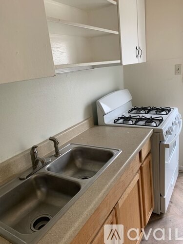 A kitchen with a stove, sink, and cabinets.