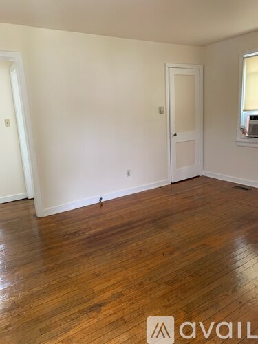 A room with wooden flooring and white walls.