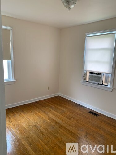 A room with wooden floors and a window with blinds.