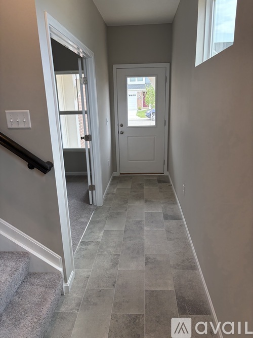 A hallway with a tiled floor and a white door.