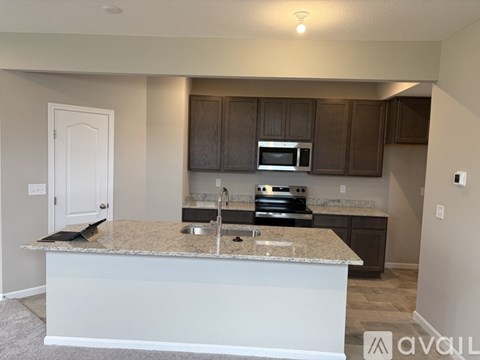 A kitchen with a granite countertop and dark brown cabinets.