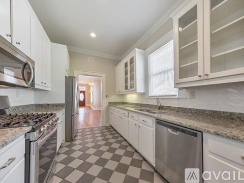 A kitchen with white cabinets and a checkered floor.