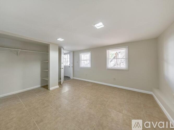 A spacious room with beige tiles on the floor and white walls.