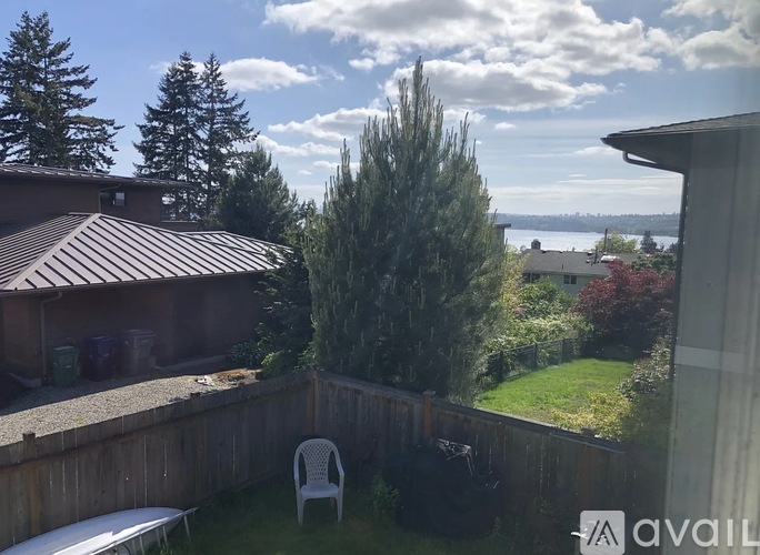 A backyard with a white chair and a brown roofed house.