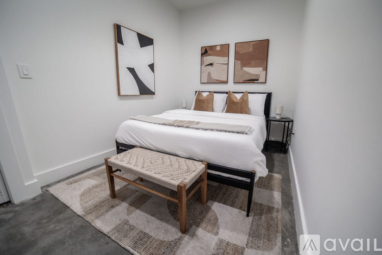 A bedroom with a white bed and a bench in front of it.