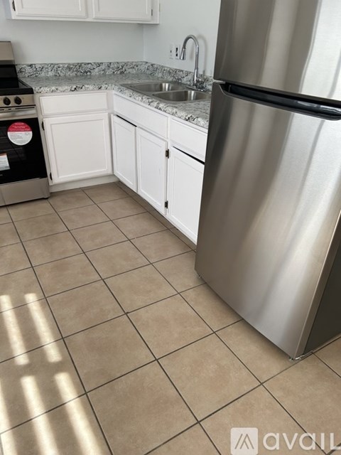 A kitchen with a stainless steel refrigerator and white cabinets.