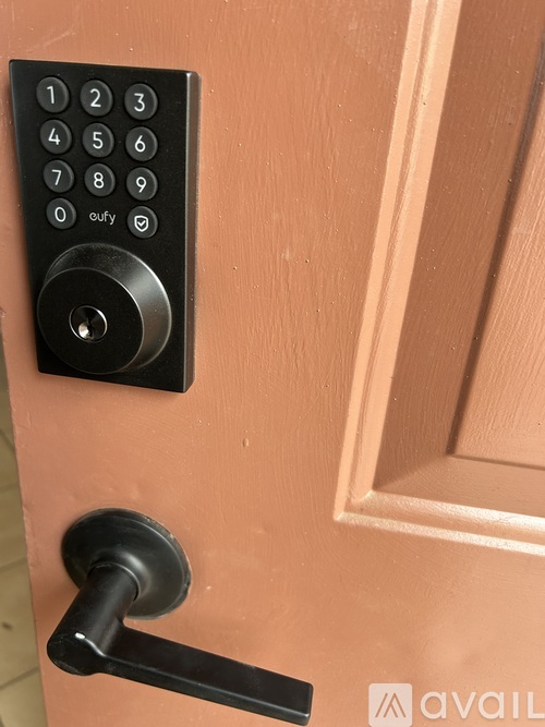 A black keypad is mounted on a peach door.