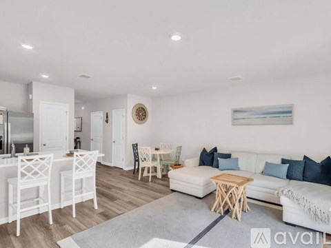 A living room with a white couch and a dining table with chairs.
