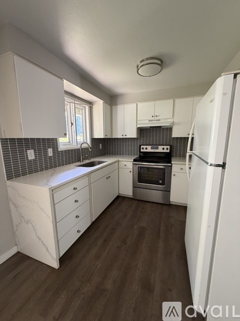 A kitchen with white cabinets and a white fridge.
