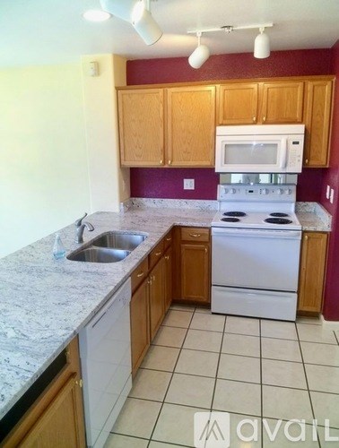 A kitchen with a white stove top oven and a white microwave above the stove.