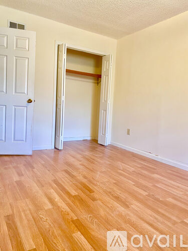 A room with a white door and a white wall with a wooden floor.