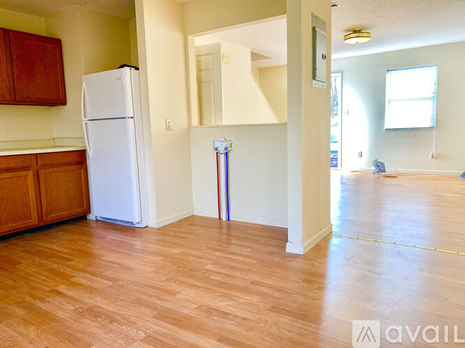 A white refrigerator in a room with wooden floors and a mirror on the wall.