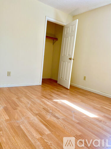 A room with a white door and wooden flooring.