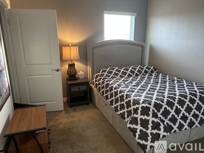 A bedroom with a bed, nightstand, and lamp.