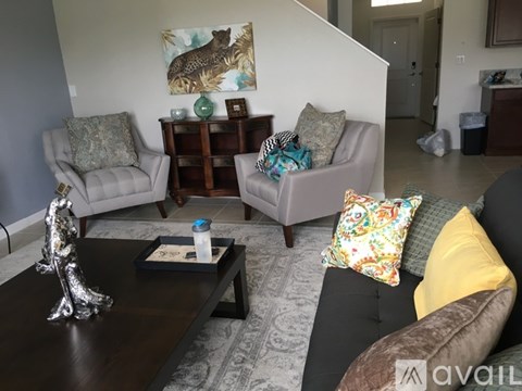 A living room with a couch, two chairs, a coffee table, and a painting on the wall.